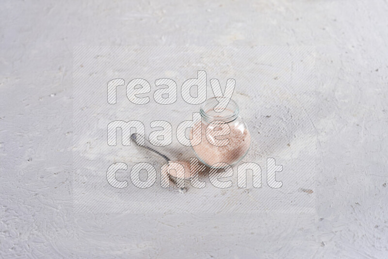 A glass jar full of fine himalayan salt on white background
