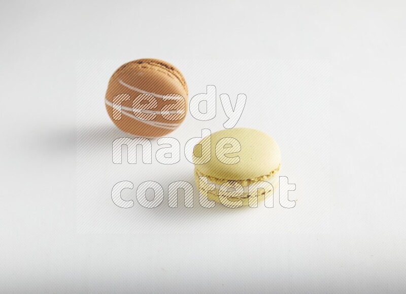 45º Shot of of two assorted Brown Irish Cream, and Yellow Lime macarons on white background