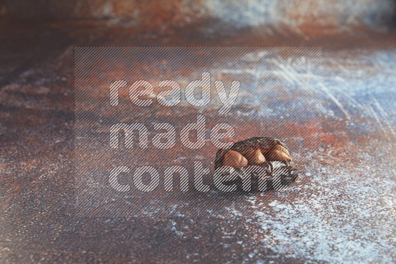 one hazelnut stuffed madjoul date on a rustic reddish background