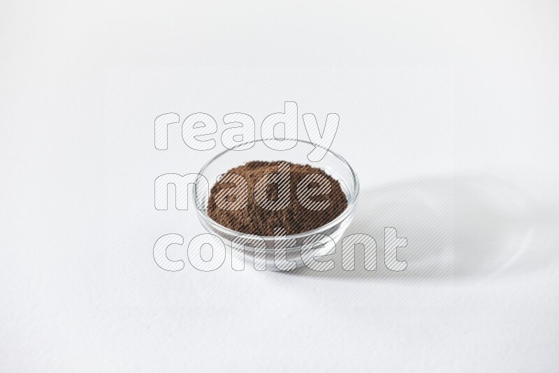 وعاء زجاجي ممتلئ ببودرة القرنفل على أرضية بيضاء