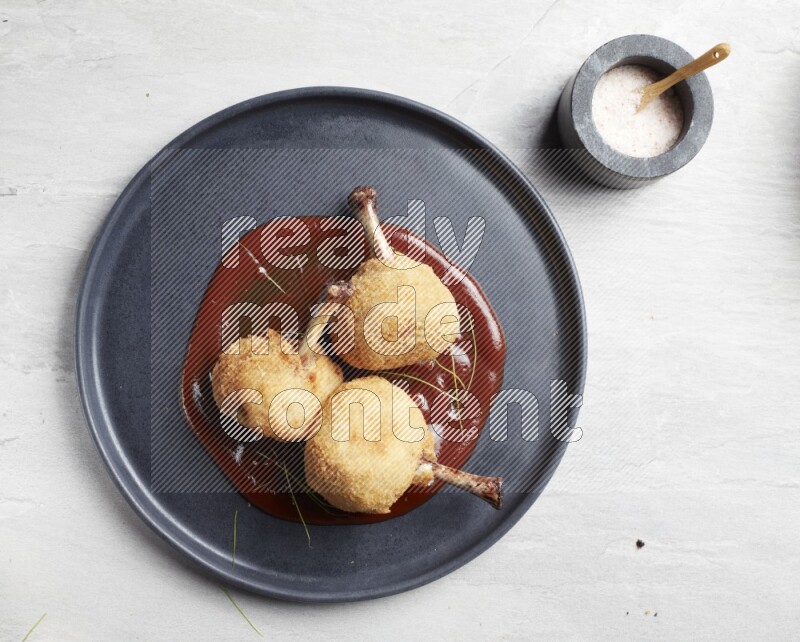 breaded drumstick on round dark grey pottery plate on grey textured countertop