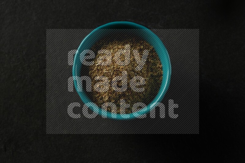 turquoise pottery round sauce bowl filled with herbs on grey textured countertop