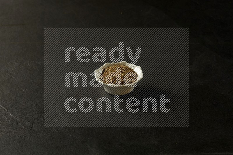 white ceramic round sauce bowl filled with herbs on grey textured countertop