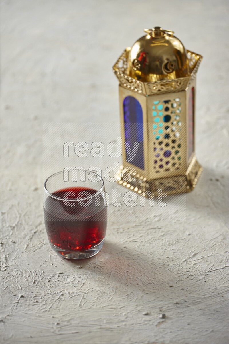 A golden lantern with different drinks, dates, nuts, prayer beads and quran on textured white background