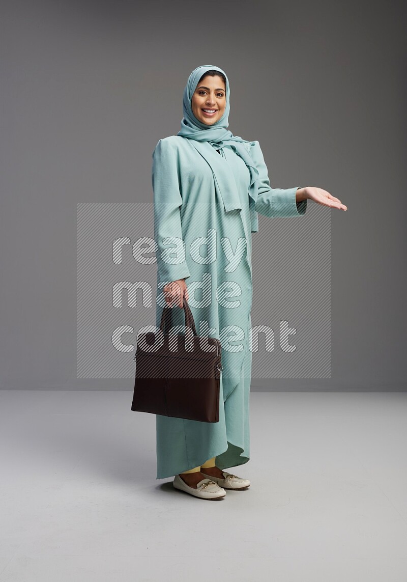 Saudi Woman wearing Abaya standing holding bag on Gray background