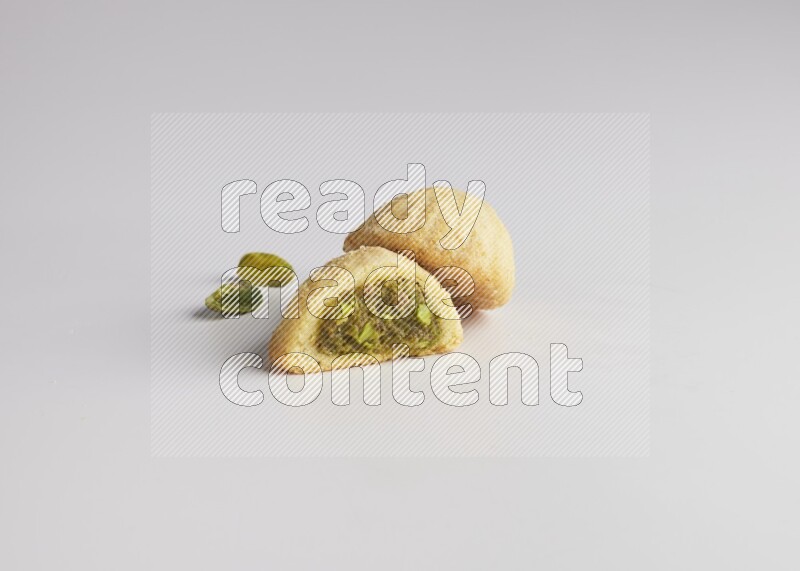 Two Pieces of Maamoul filled with pistachio paste  one of them is cut direct on white background