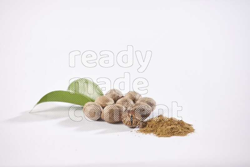 Nutmeg whole seeds with nutmeg powder beside it on a white flooring