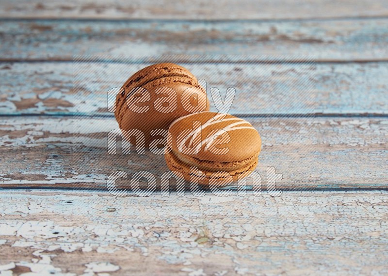 45º Shot of of two assorted Brown Irish Cream, and Brown Coffee macarons on light blue background