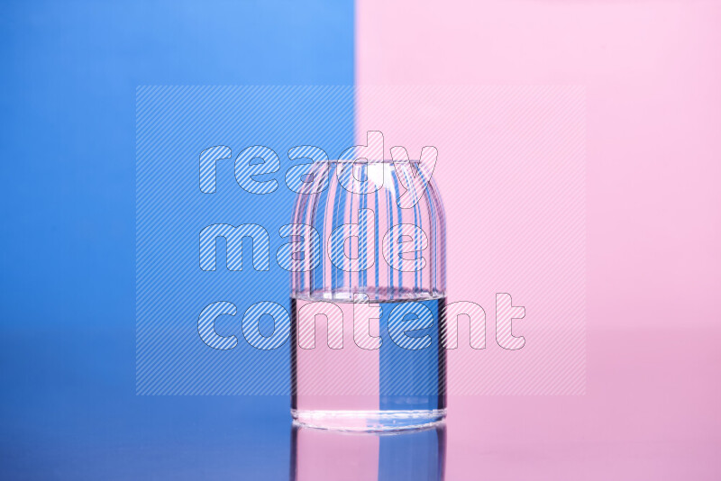 The image features a clear glassware filled with water, set against blue and rose background