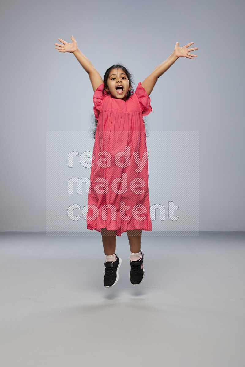 A girl standing interacting with the camera on gray background