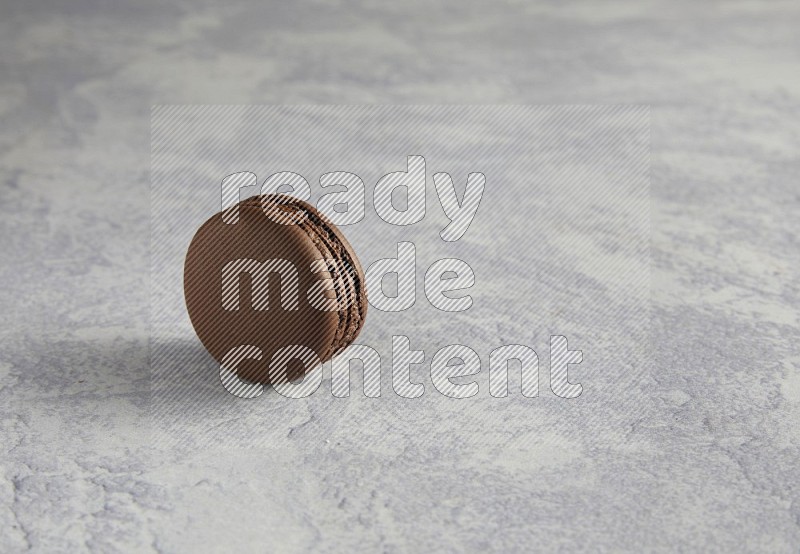 45º Shot of Brown Dark Chocolate macaron on white  marble background