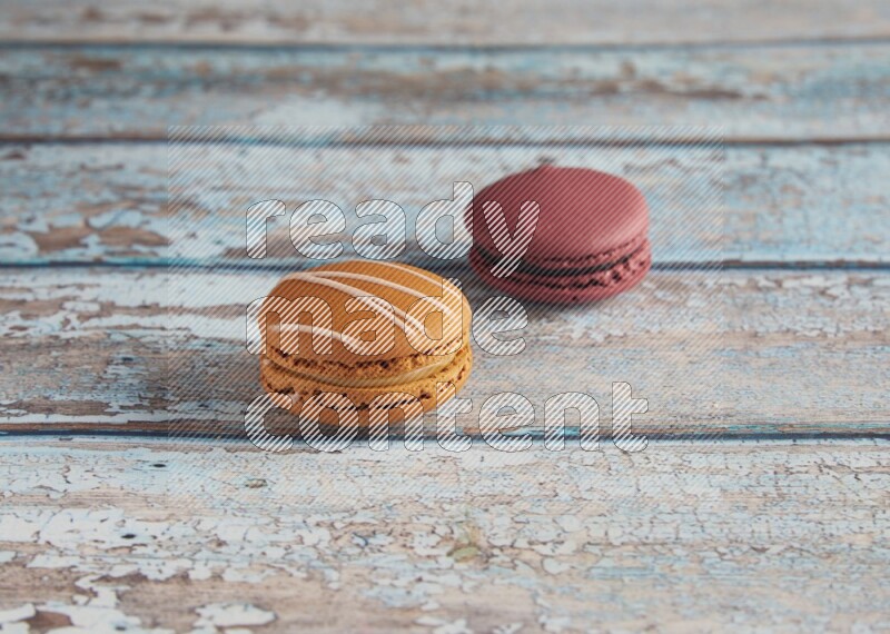 45º Shot of of two assorted Brown Irish Cream, and Red Cherry macarons  on light blue background