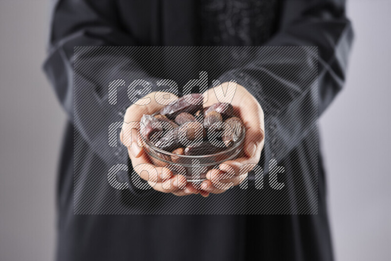 Woman in abaya holding dates in different positions