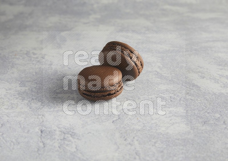 45º Shot of two Brown Dark Chocolate macarons  on white  marble background