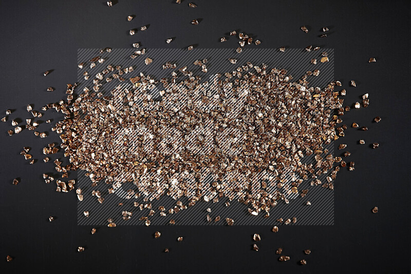 Bronze shimmering fragments of glass scattered on a black background