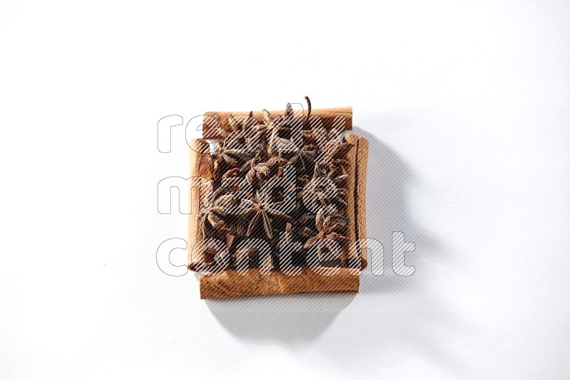 A single square of cinnamon sticks full of star anise on white flooring