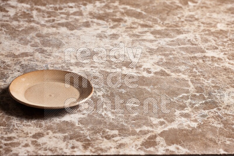 A beige pottery plate on beige marble background