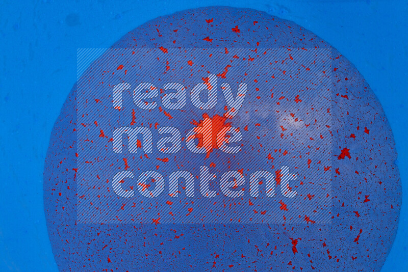The image captures a dramatic splatter of red paint over a blue backdrop