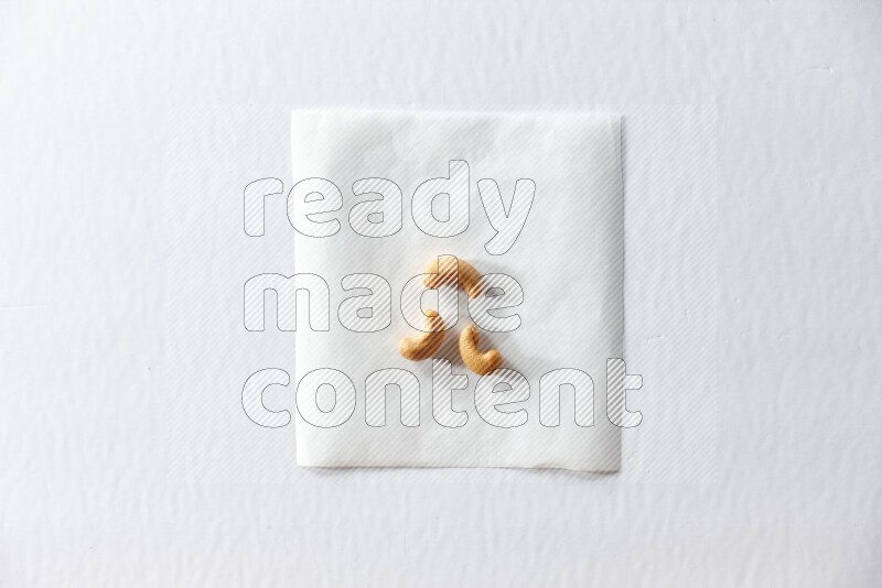 3 cashews on a piece of paper on a white background in different angles