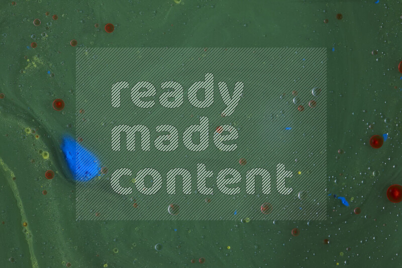 The image captures a dramatic splatter of yellow, red and blue paints over a green backdrop