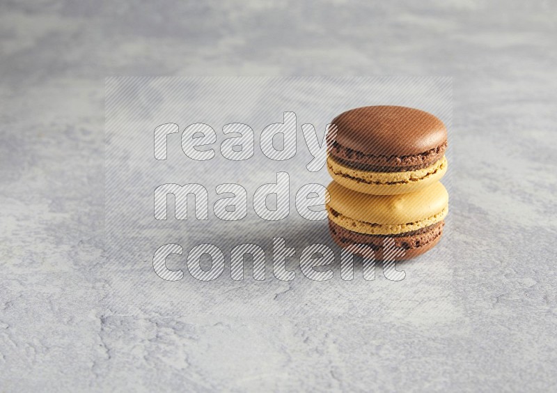 45º Shot of two Yellow and Brown Chai Latte macarons r on white  marble background