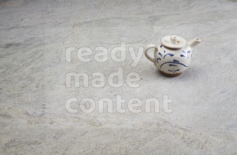 A Pottery Teapot On Grey Marble Flooring