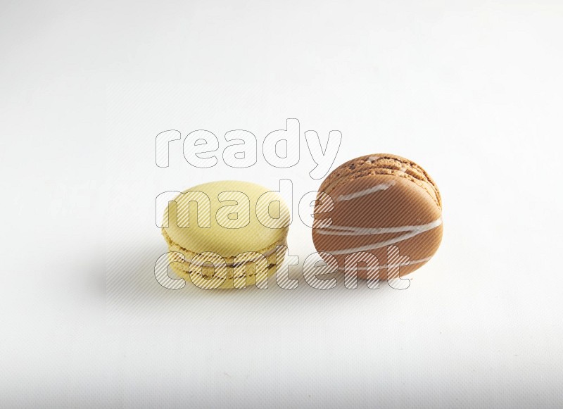 45º Shot of of two assorted Brown Irish Cream, and Yellow Lime macarons on white background