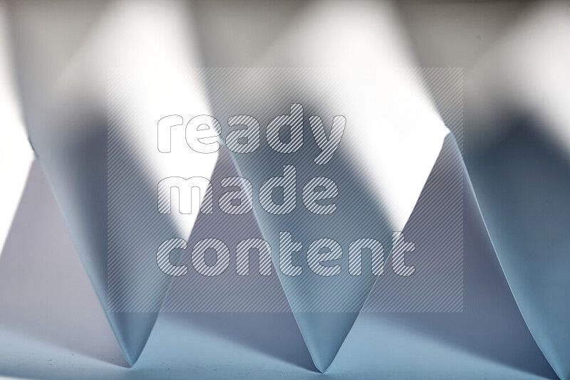 A close-up abstract image showing sharp geometric paper folds in white and blue gradients
