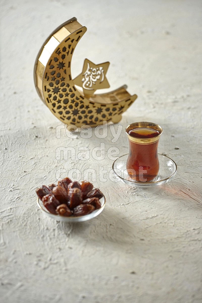 A crescent lantern with drinks, dates, nuts, prayer beads and quran on textured white background