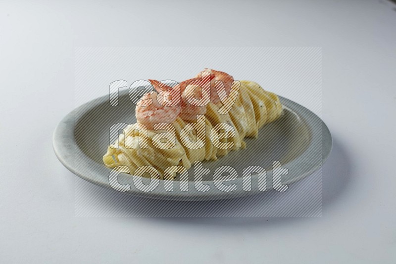 Fettuccini white sauce pasta with shrimp in a white plate on a white background