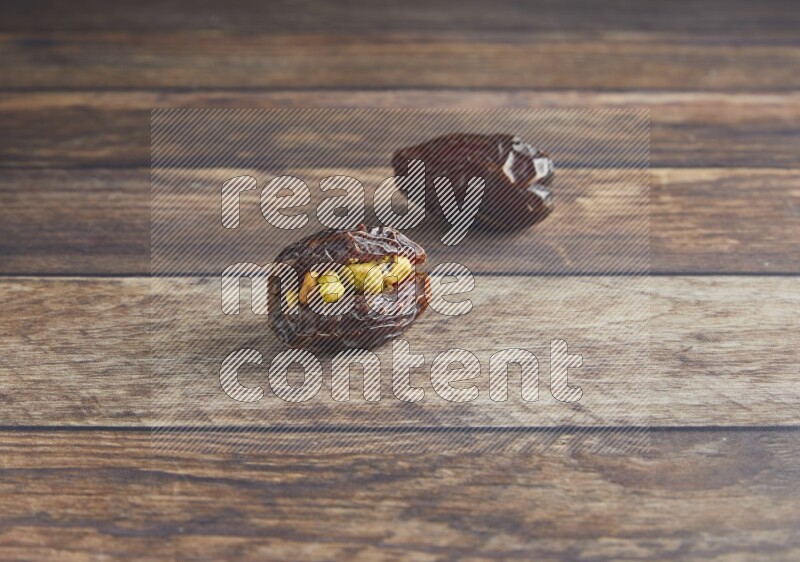 two pistachio stuffed madjoul date on a wooden background