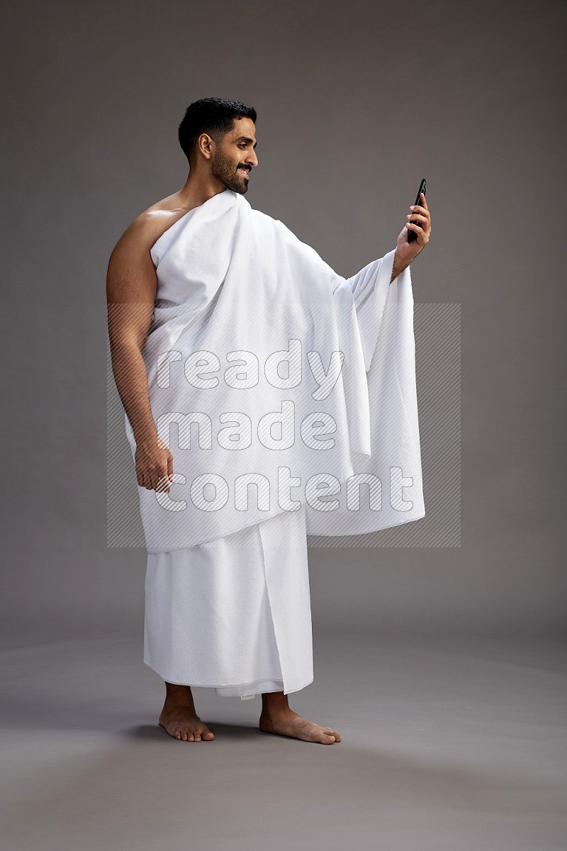 A man wearing Ehram Standing taking selfie on gray background