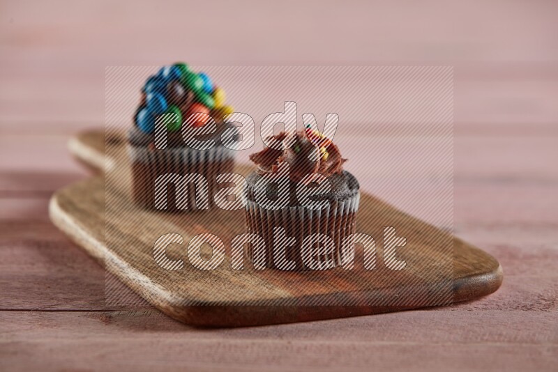 Chocolate mini cupcake topped with chocolate cream on a wooden board