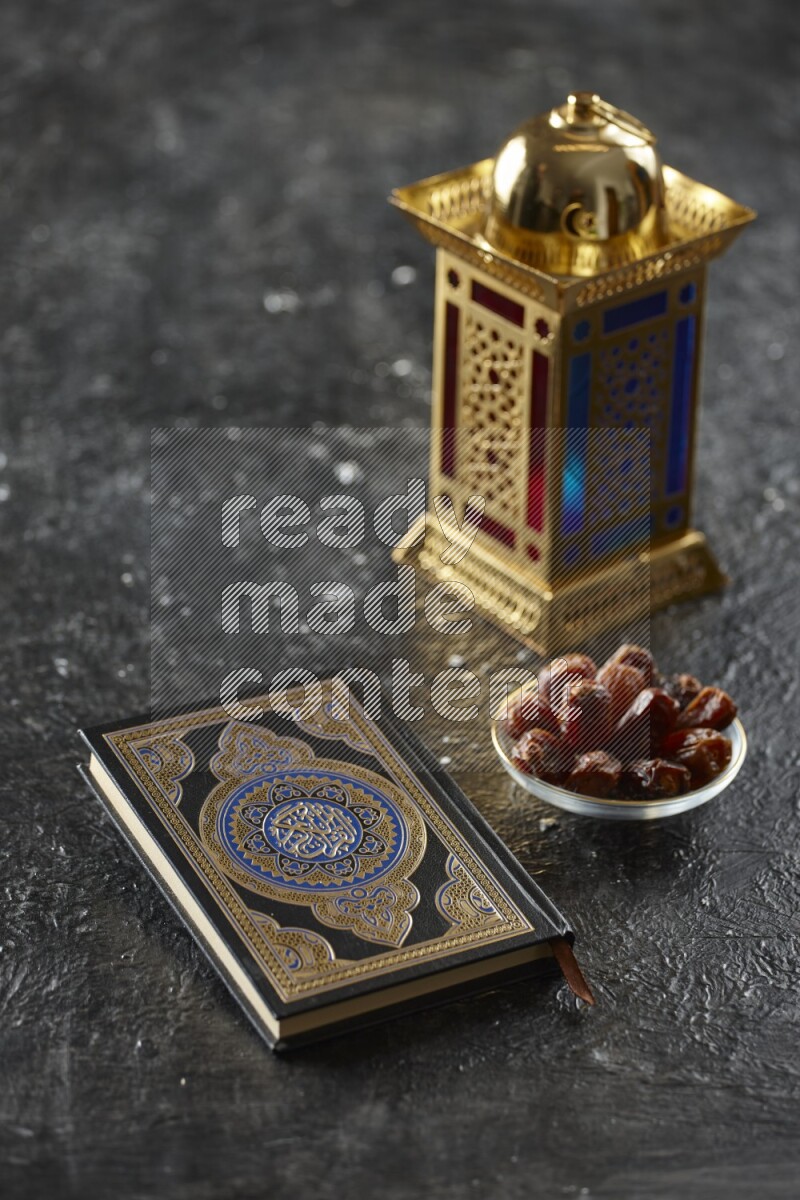 A golden lantern with different drinks, dates, nuts, prayer beads and quran on textured black background