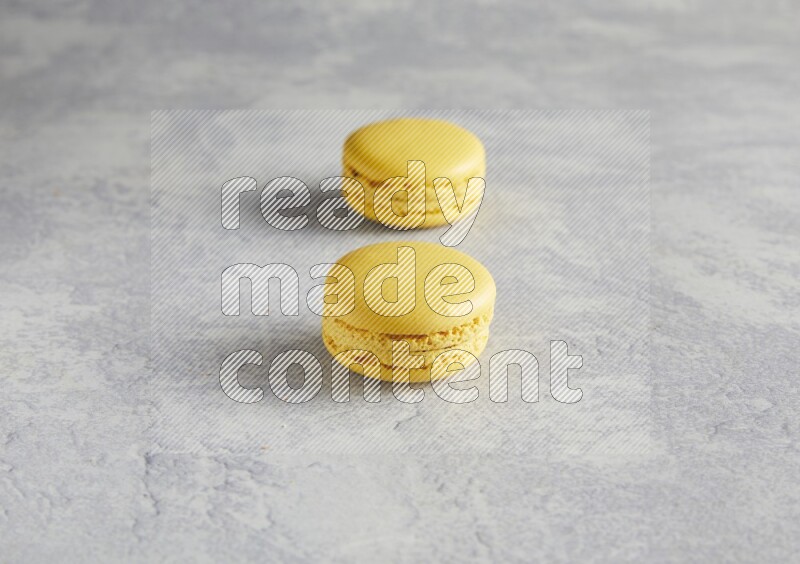 45º Shot of two Yellow Lemon macarons  on white  marble background