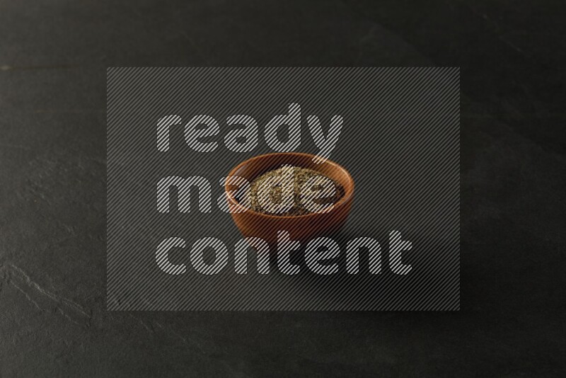 wooden round sauce bowl filled with herbs on grey textured countertop