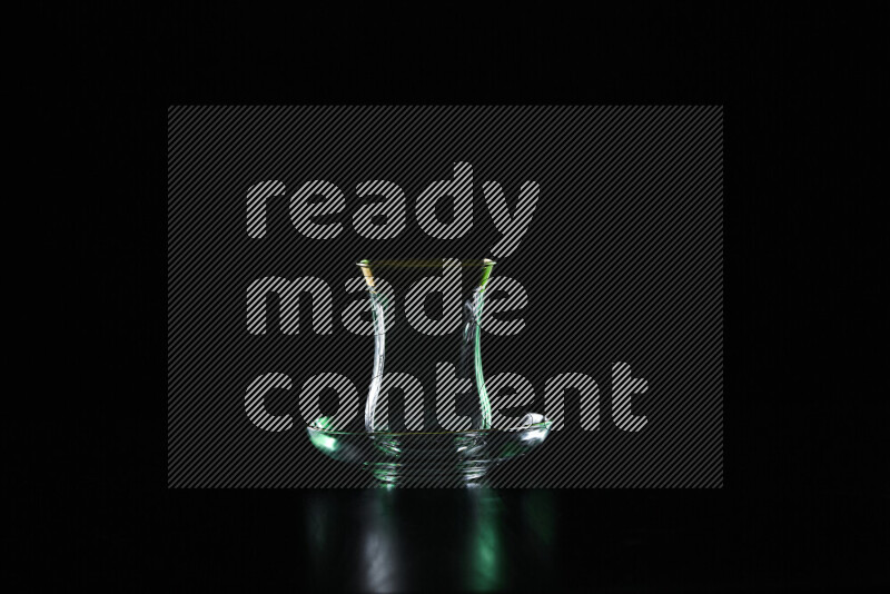 Glassware with rim light in green and white against black background