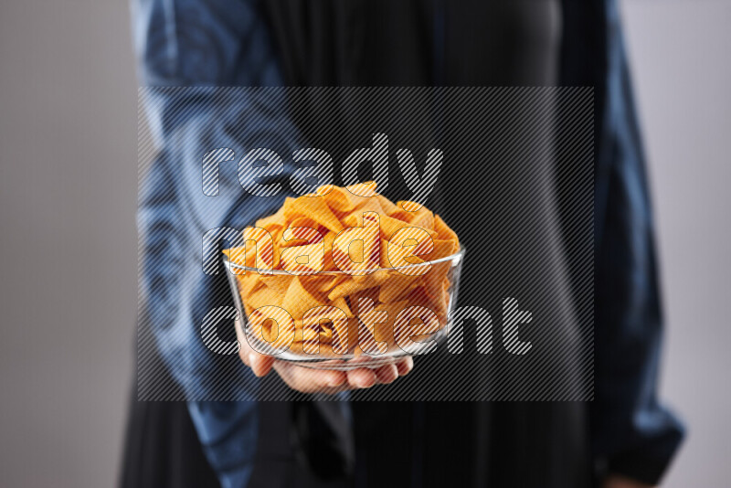 Woman in abaya holding different kinds of snacks in different positions
