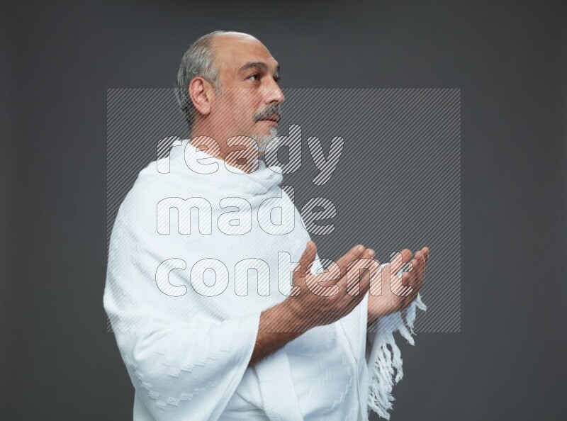 A man wearing Ehram Standing dua'a on gray background