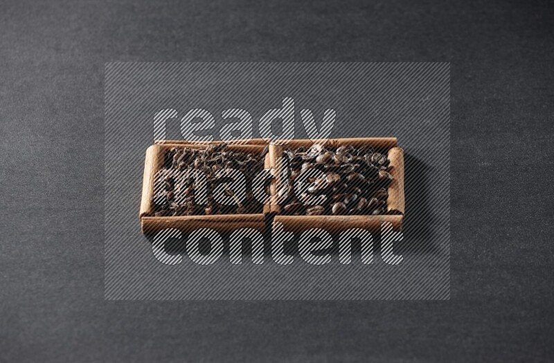 مربعان من أعواد القرفة ممتلئان بحبوب القهوة والقرنفل علي خلفية سوداء