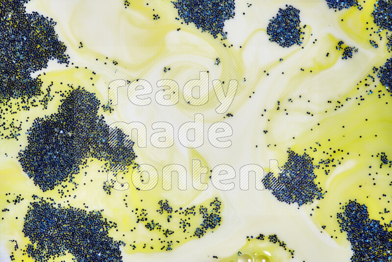 A close-up of sparkling blue glitter scattered on swirling yellow background