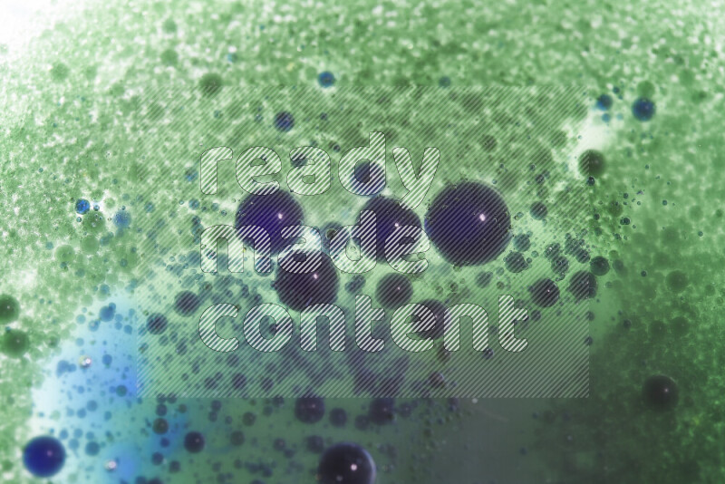 لقطات مقربة لقطرات ألوان مائية خضراء وزرقاء على سطح الزيت على خلفية بيضاء