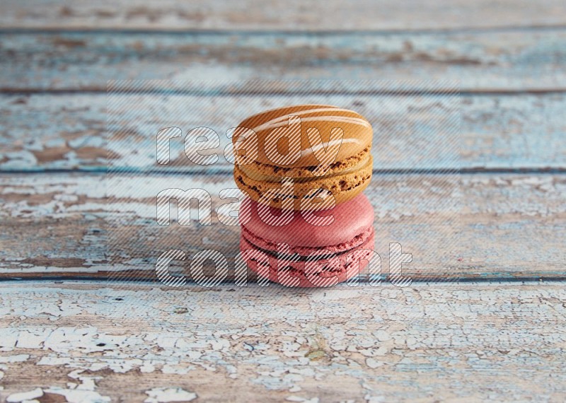 45º Shot of of two assorted Brown Irish Cream, and Pink Raspberry macarons on light blue background