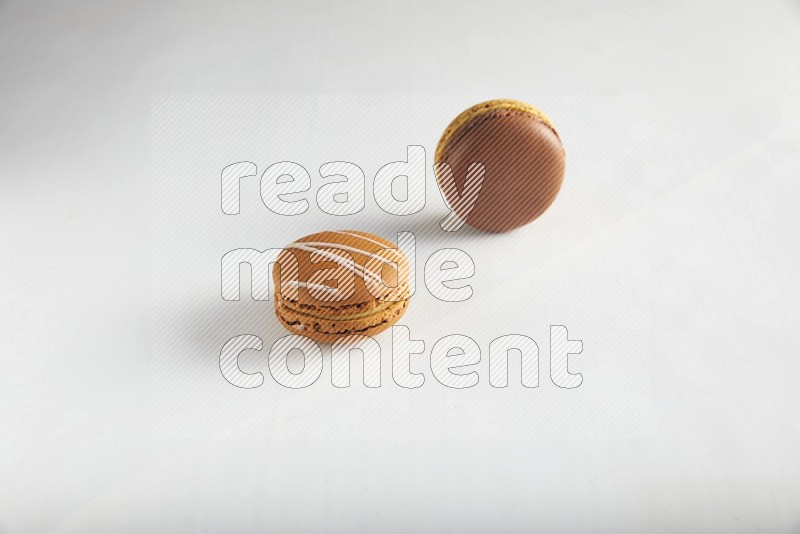 45º Shot of of two assorted Brown Irish Cream, and Yellow, and Brown Chai Latte macarons on white background