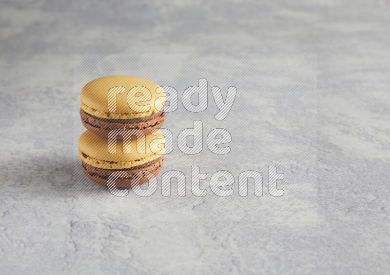 45º Shot of two Yellow and Brown Chai Latte macarons r on white  marble background