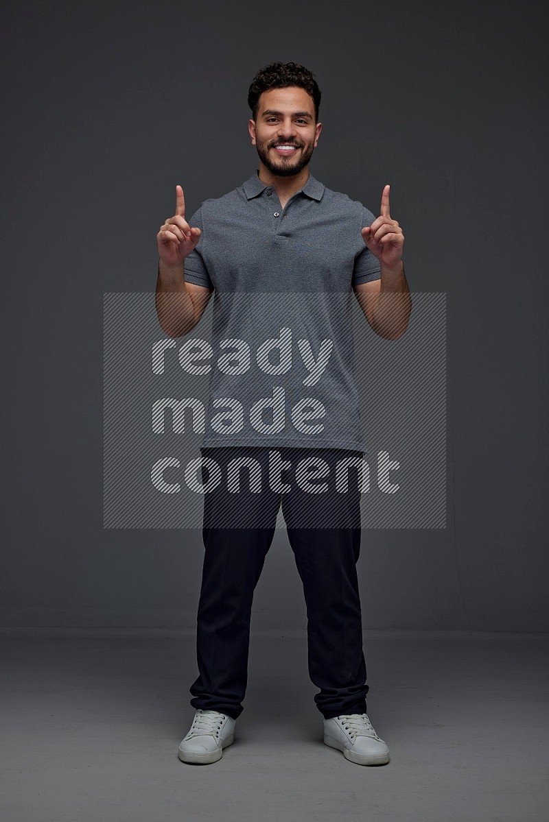 A man wearing casual standing and making multi hand gestures eye level on a gray background