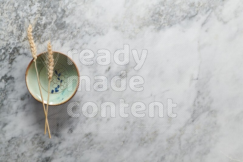 Wheat stalks on decorative pottery plate on grey marble background