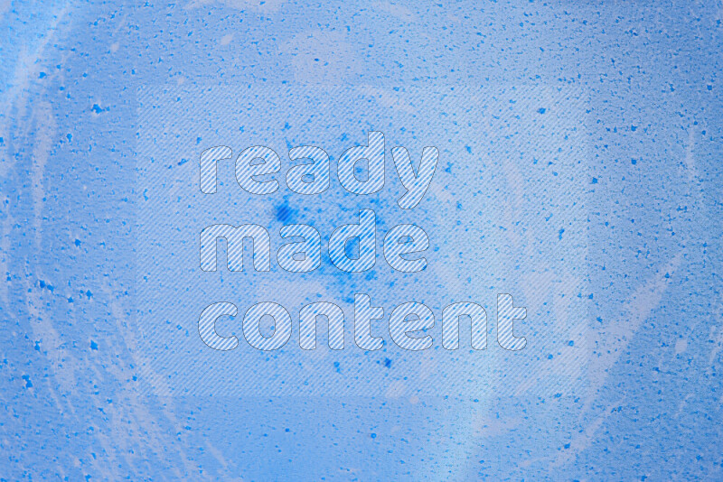 The image captures a dramatic splatter of blue paint over a blue backdrop