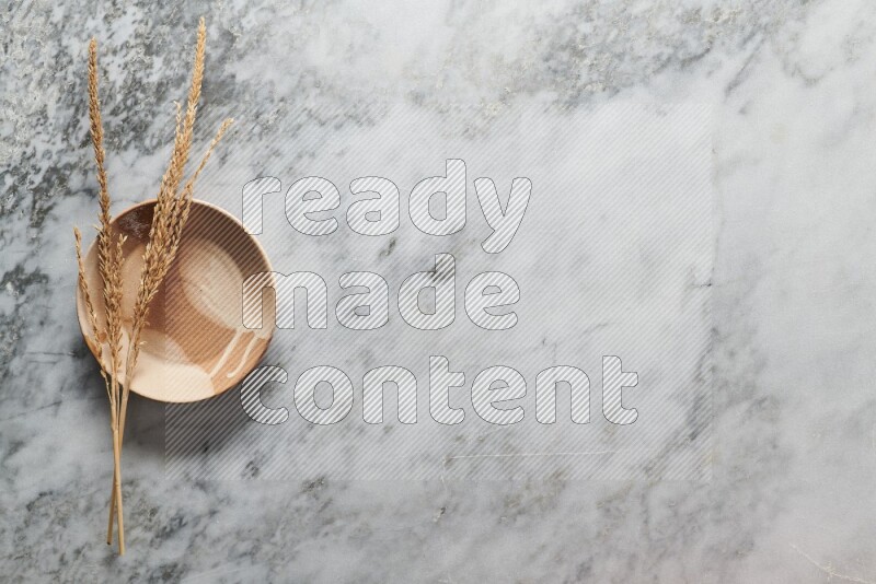 سنابل من القمح علي طبق فخاري متعدد الألوان علي خلفية من الرخام الرمادي