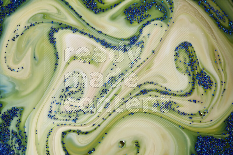 A close-up of sparkling blue glitter scattered on swirling blue and green background